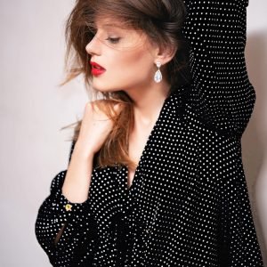 Mujer con vestido negro de puntos blancos, representando la moda sostenible y elegante con un estilo sofisticado y atemporal.