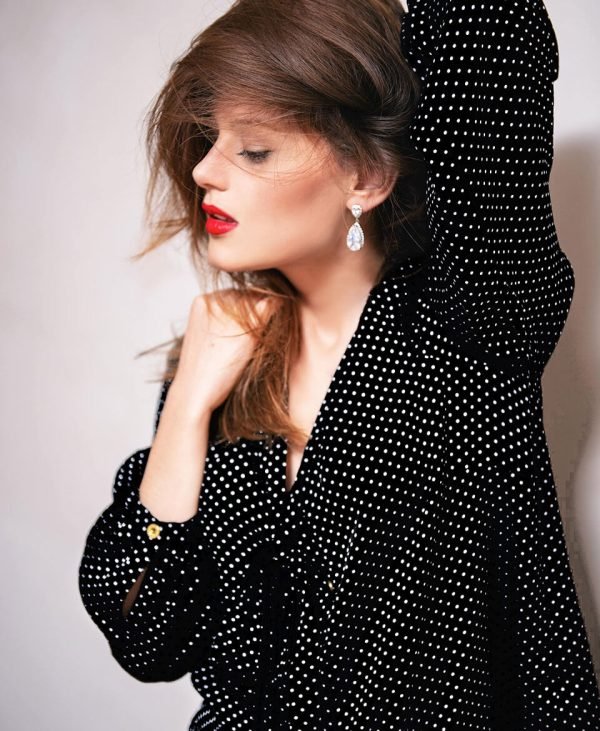 img-06-a-black Mujer con vestido negro de puntos blancos, representando la moda sostenible y elegante con un estilo sofisticado y atemporal.